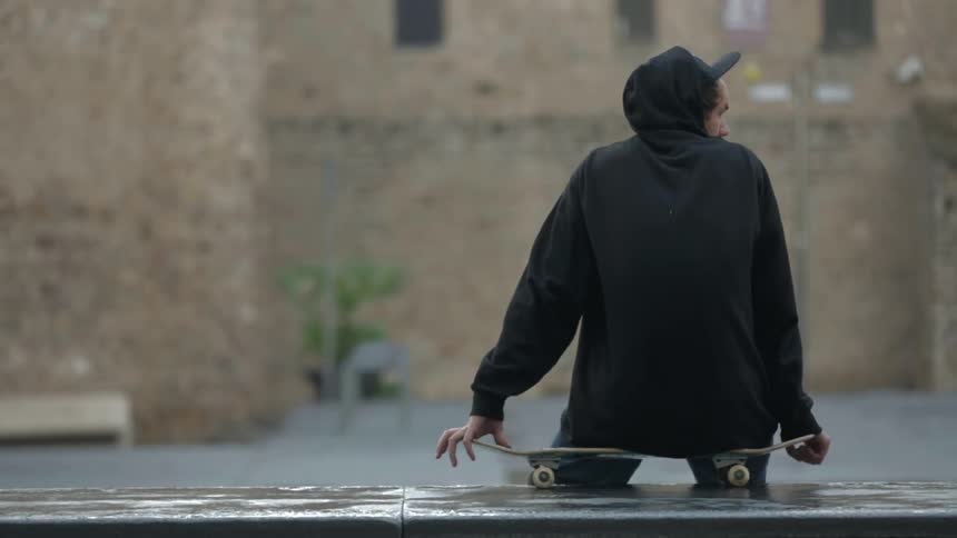 Man sitting on a skateboard in front of a building