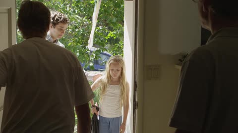 Two men open a door to visitors on a sunny day