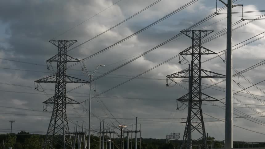 Tall power lines with clouds passing overhead