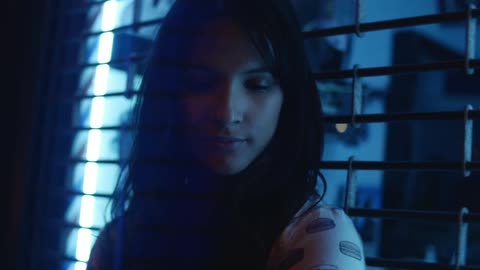 A woman smiles standing in front of a metal gate at night