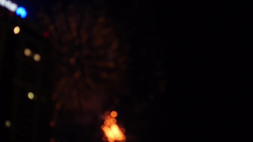 Fireworks exploding in the night sky by a building