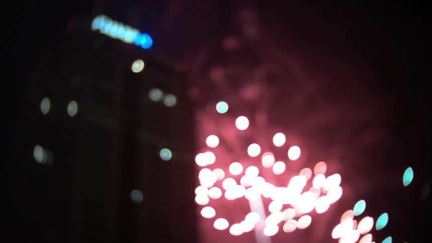 Fireworks exploding in the night sky in front of a building
