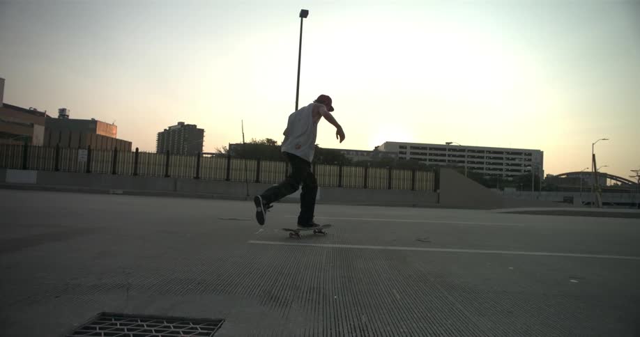 Man skateboarding in a lot at sunrise