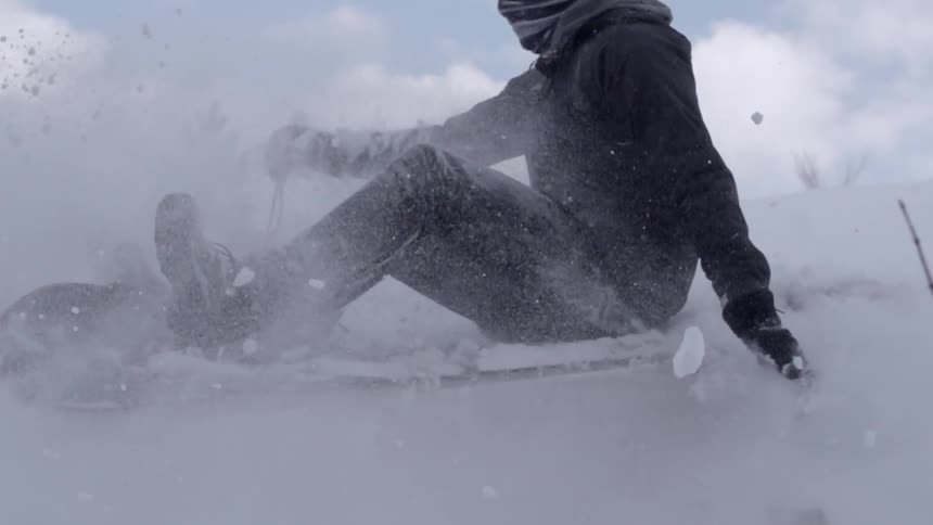 A person on a sled goes over a jump on a snow covered hill