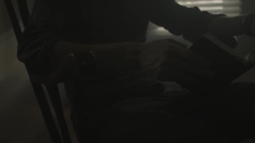 A man sits in a dark room reading a book