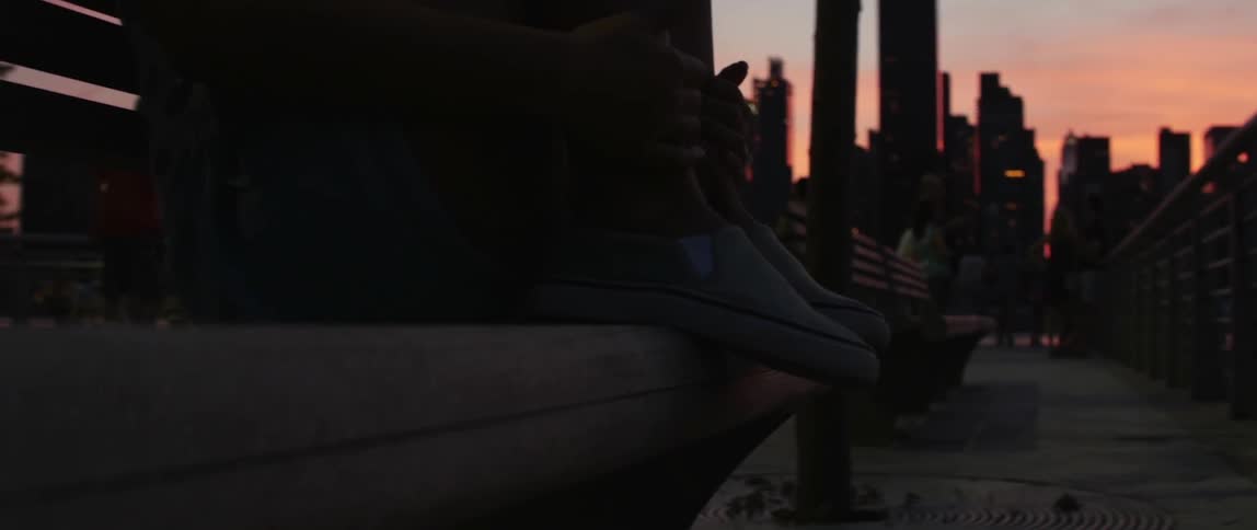 A person sits on a city bench at dusk