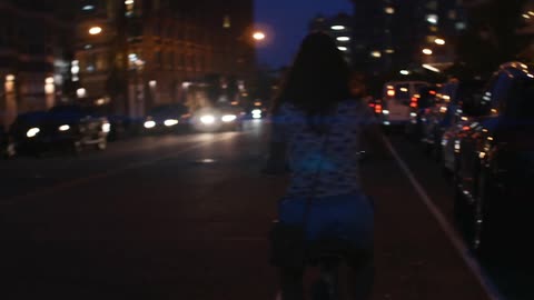 A young woman riding a bicycle down a city street at night