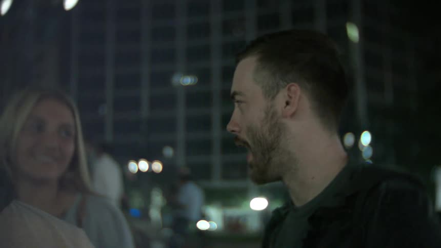 Man talking with some friends near a crowd at night