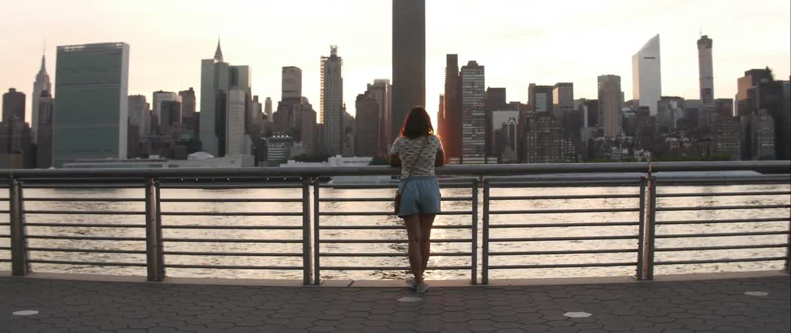 Woman stands against railing looking at city skyline