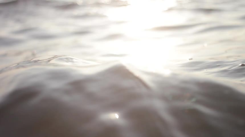 Close up of water rippling with a sunset reflection upon it
