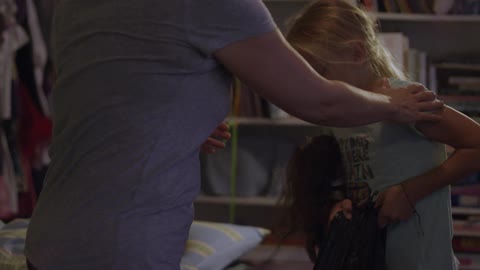 A woman walks a little girl into a room with another sleeping girl