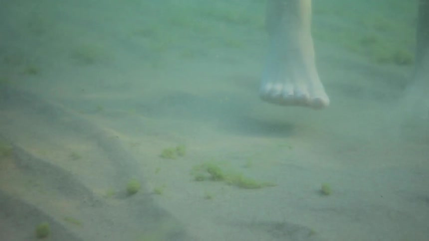 A person's feet jumping up and down underwater