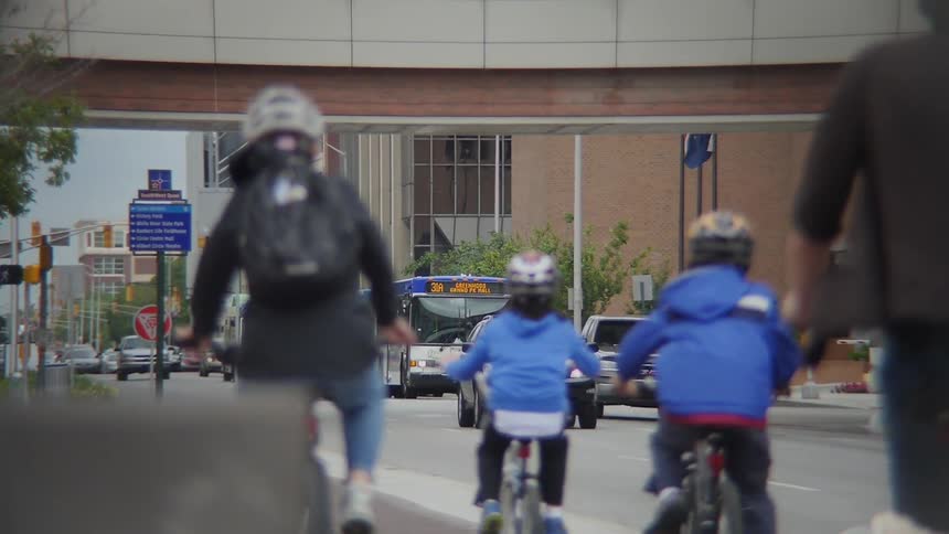 A family bicycles down a city sidewalk