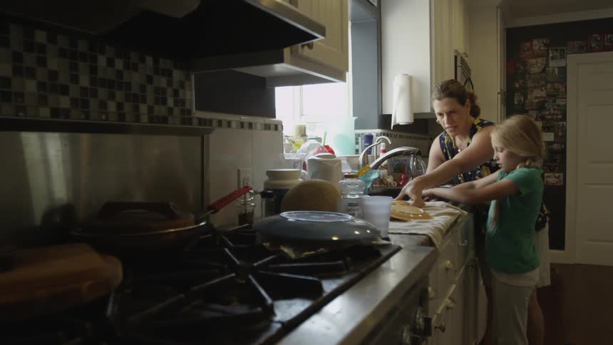 Woman and girl doing dishes at a sink by the window