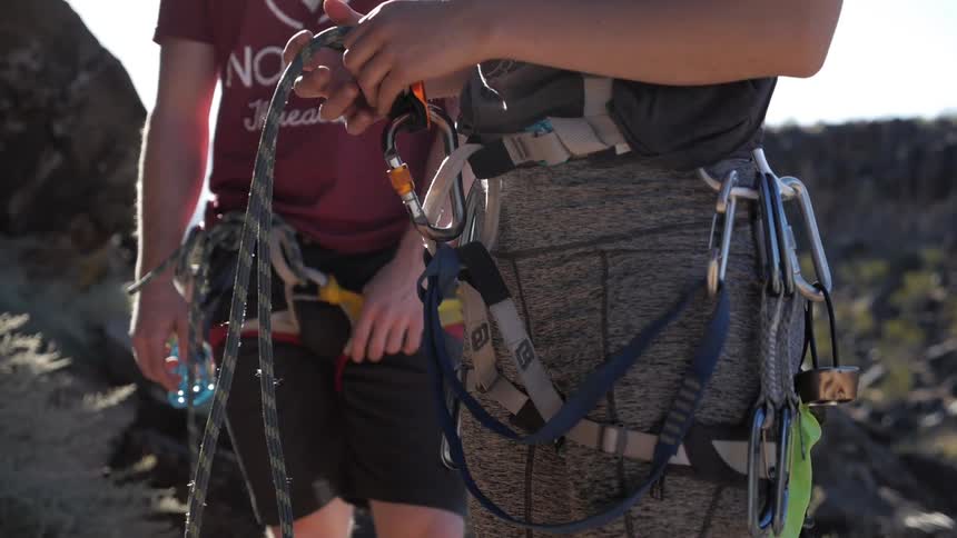 Rock climbers with clips and ropes attached to their hips