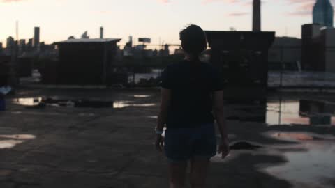 A woman walking around puddles on a building rooftop in the city