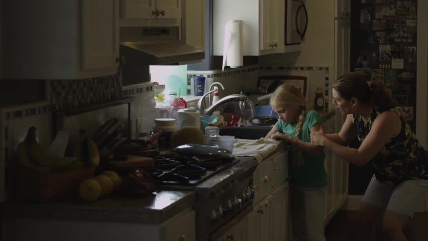 A girl throws dishes onto the kitchen floor