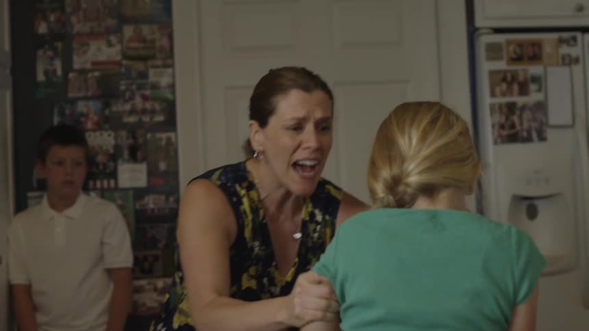 A brunette woman forcibly pulling a young blonde girl around, roughly grabbing her arms, shaking her and asking her what was wrong with her