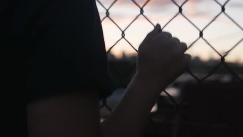 A person standing next to a fence