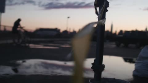 A person holding a bike as the sun sets