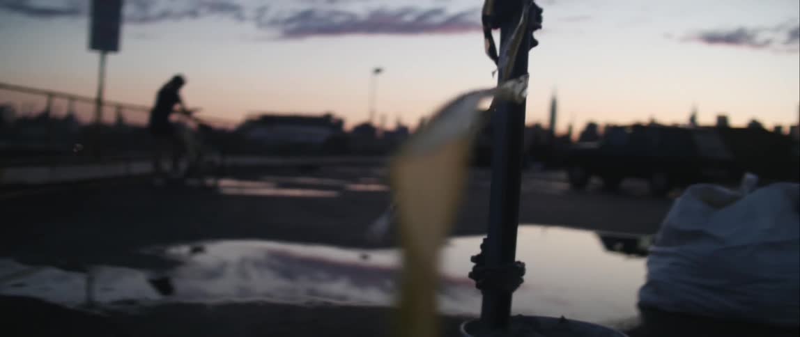 A person holding a bike as the sun sets