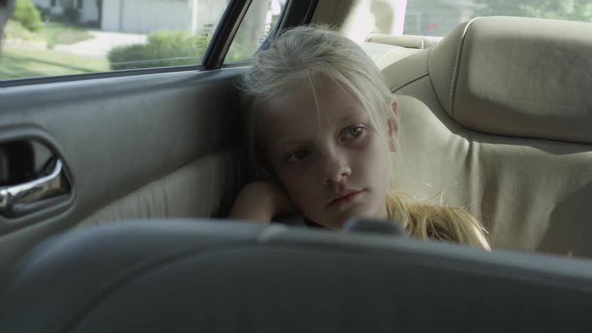 Girl sitting in a car's backseat as it is driving