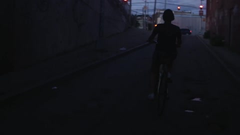 Person riding a bike down a dark street at dusk