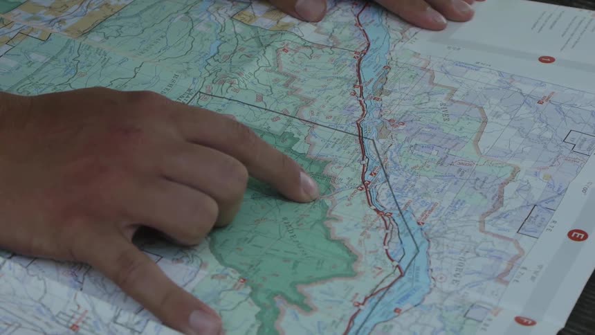 A person looks and points at places on a map
