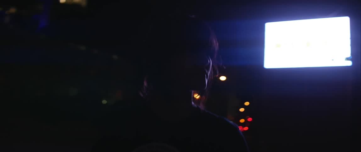 Woman standing in dark room with bright screen behind her