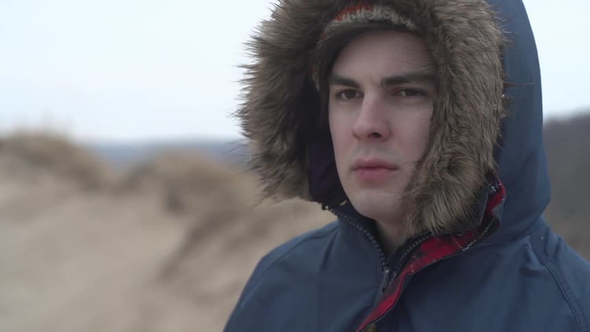 A man wearing a fur lined coat looks around