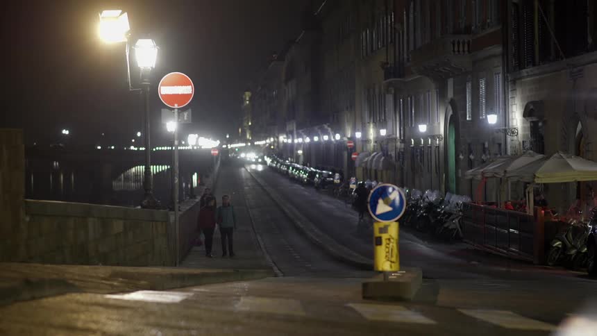Night time view of a city block with cars passing in front
