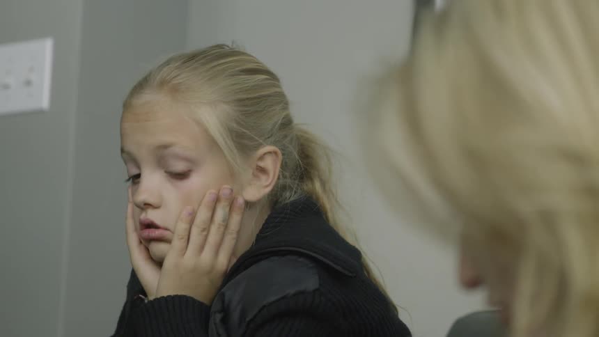 A bored young girl sits in a room listening to her mother