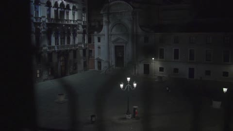 A lit courtyard streetlight shines between several buildings