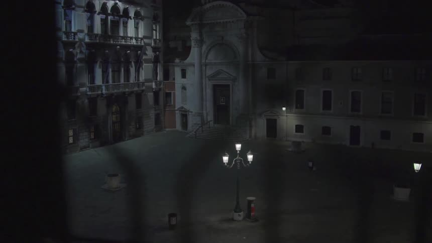 A lit courtyard streetlight shines between several buildings
