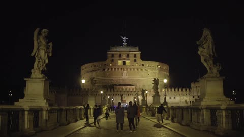 People walking across a bridge at night