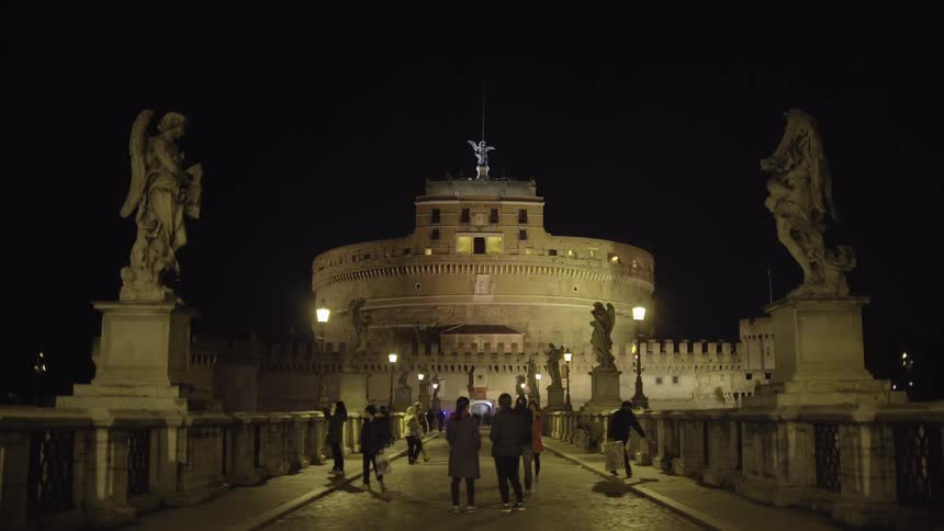 People walking across a bridge at night