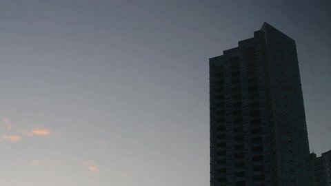 Time lapse of clouds passing by a tall building