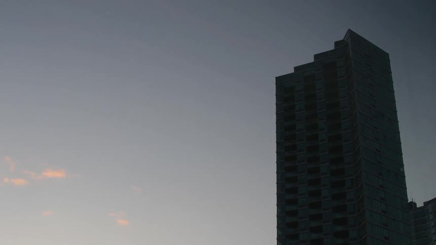 Time lapse of clouds passing by a tall building