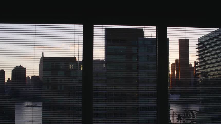 View of a city behind blinds of a window