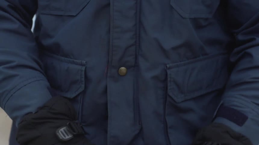 A man in gloves and a coat loads a flare gun
