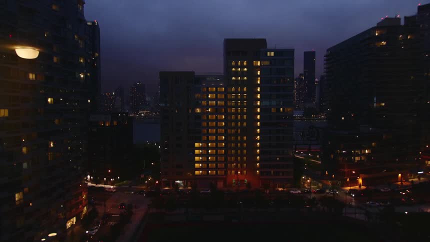 A timelapse view at night of a city with many tall buildings, while the thunder clouds roll through