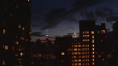 Time-lapse of clouds moving across a city scene at dusk and into night