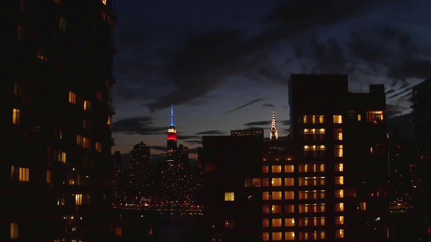 Time-lapse of clouds moving across a city scene at dusk and into night
