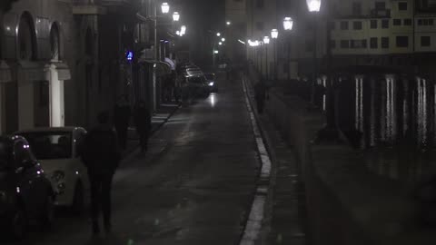 People walk down a city street at night