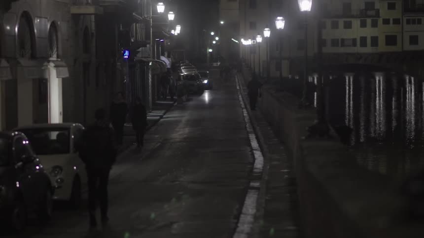 People walk down a city street at night