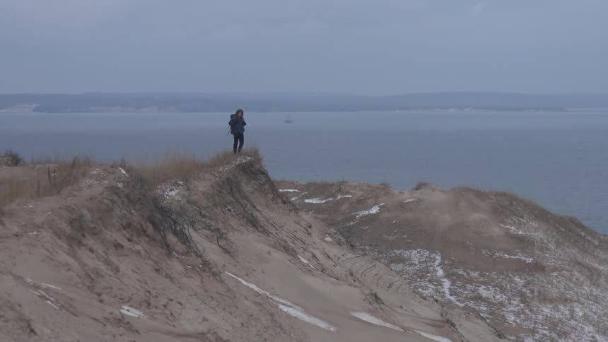 Person hiking up a hill near the coast on a cloudy day