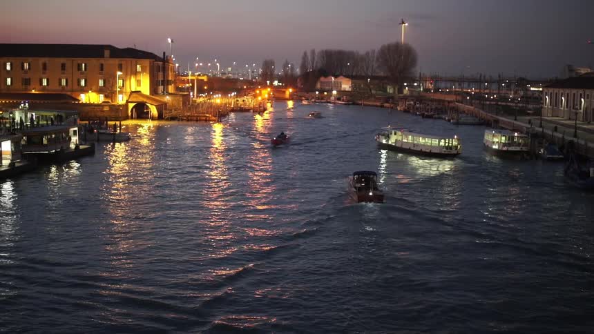Boats traveling down a small body of water at sunset