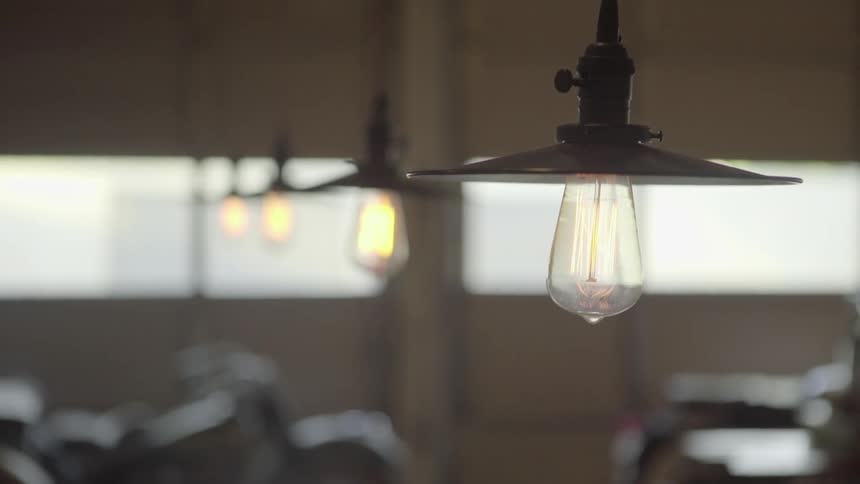 Light fixtures are hanging as a woman walks by