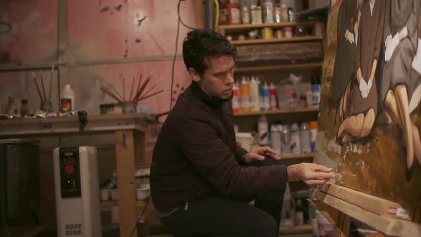 A man works on a painting in his workshop