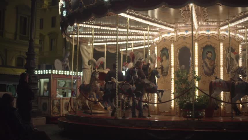 A merry go round in an old city square lit up at night